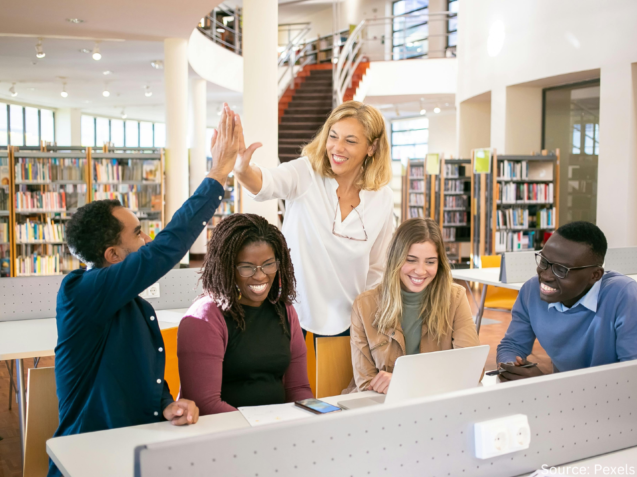 people at a desk, two are high fiving